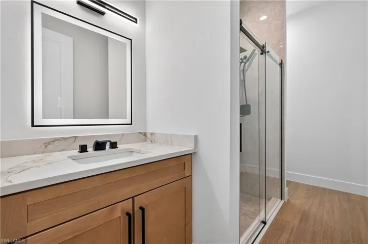 Bathroom vanity featuring a rectangular undermount sink, a stone-finish countertop, and matte black fixtures