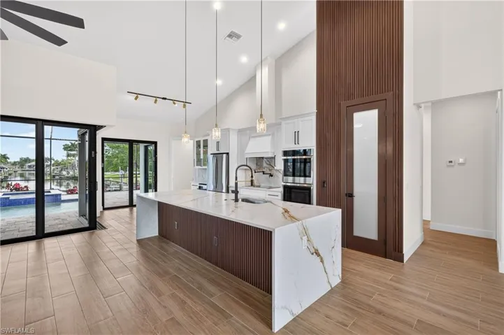 Open-concept kitchen featuring a waterfall island with a quartz countertop and integrated sink
