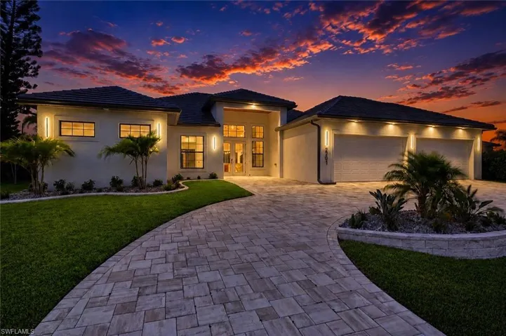 Contemporary single-story residence featuring a paved driveway, a two-car garage with individual doors, and a manicured lawn