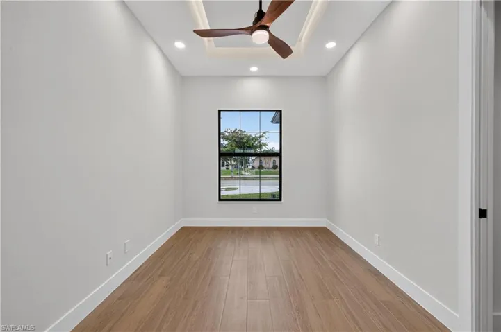 Interior room featuring wood-finish flooring, white painted walls, and a black-framed window