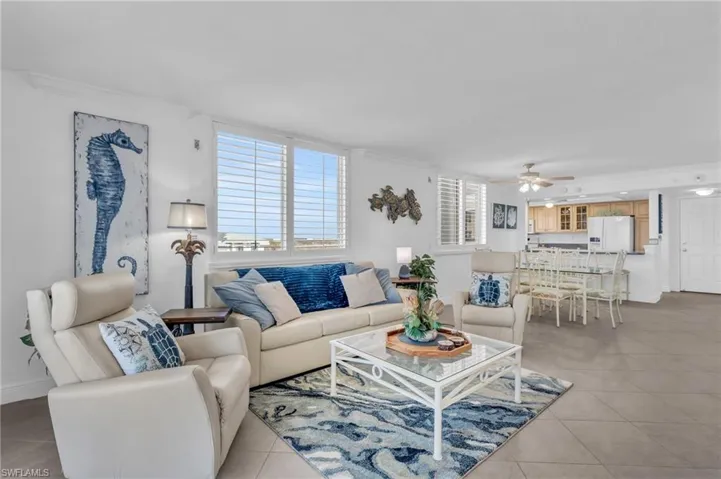 Living room featuring ceiling fan, crown molding, and light tile patterned flooring, virtually enhanced image