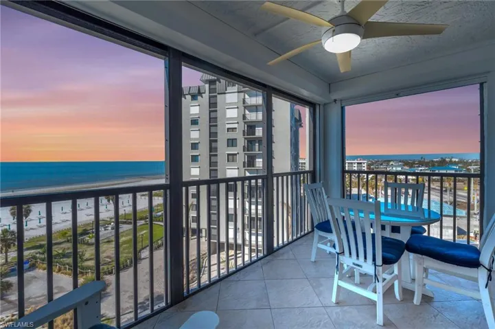VIRTUALLY ENHANCED - Balcony at dusk with ceiling fan, a water view, and a beach view virtually enhanced image