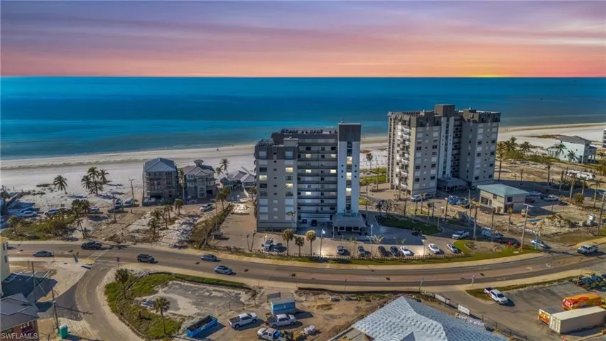 VIRTUALLY ENHANCED - Aerial view at dusk featuring a water view and a beach view