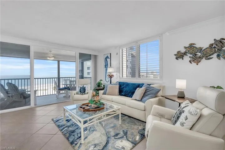 Living room with light tile patterned flooring, a water view, crown molding, and a wealth of natural light virtually enhanced image