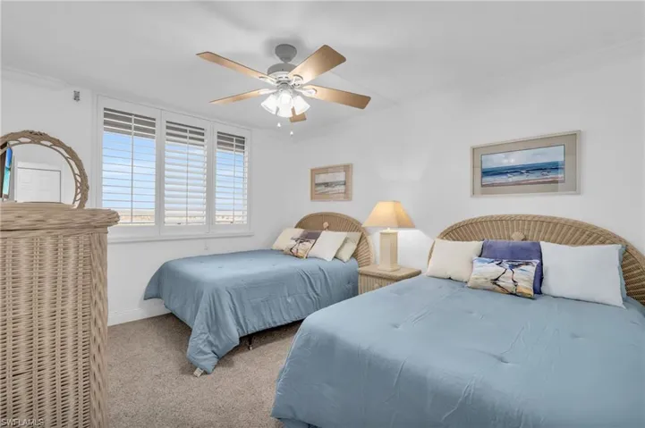 Carpeted bedroom featuring ceiling fan and crown molding