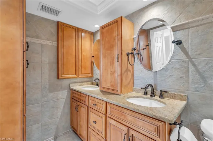 Bathroom with vanity, toilet, crown molding, and tile walls