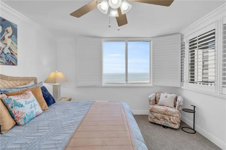 Carpeted bedroom featuring ceiling fan, a water view, and ornamental molding, virtually enhanced image