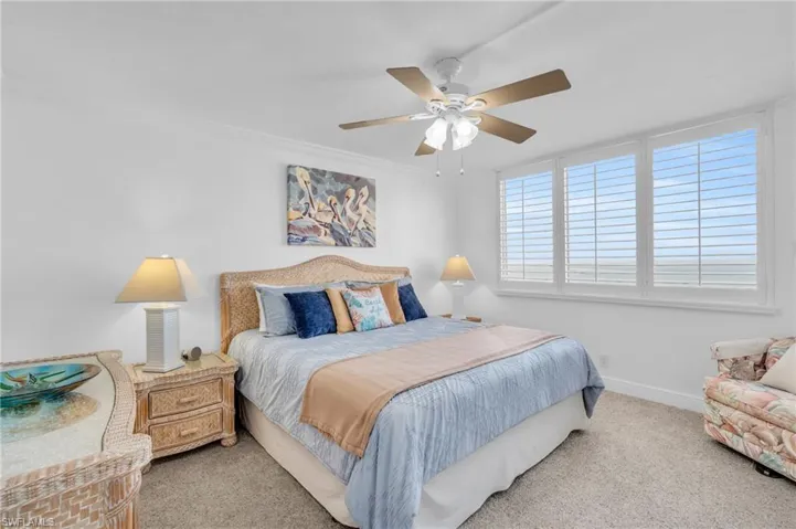 Carpeted bedroom with ceiling fan and ornamental molding, virtually enhanced image