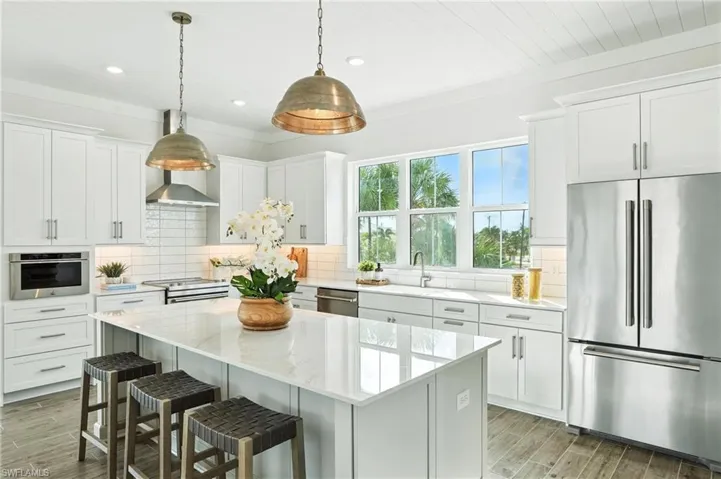 Kitchen with stainless steel appliances, white cabinets, a center island, and recessed lighting