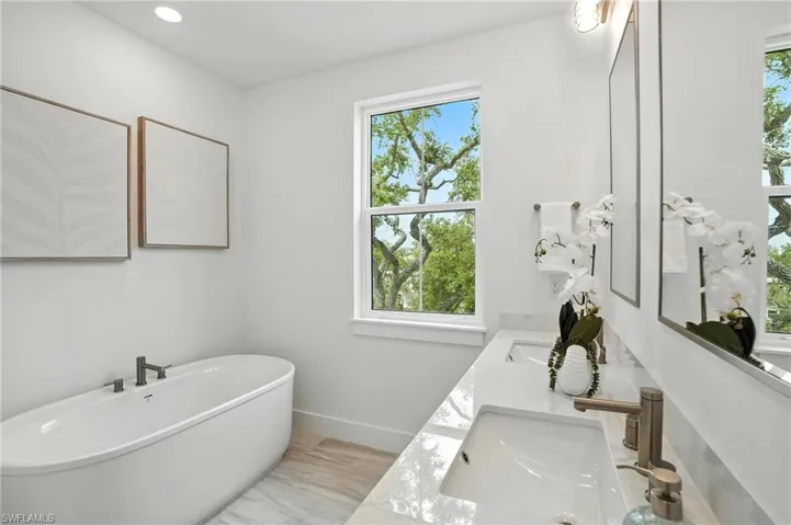 Full bathroom with plenty of natural light, a freestanding tub, double vanity, and recessed lighting
