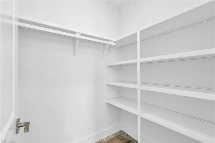 Walk in closet with hardwood / wood-style flooring