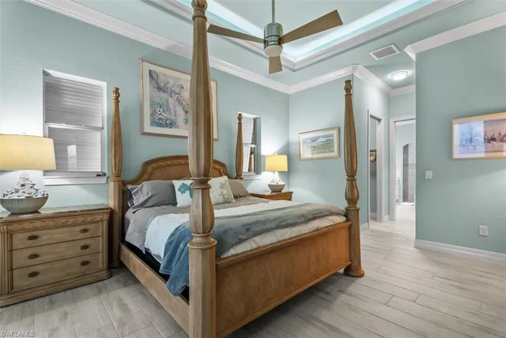 Spacious room featuring wood-finish flooring, light blue wall tones, and white crown molding
