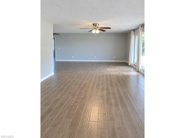Spacious interior featuring wood-finish flooring, light grey walls, and a ceiling fan