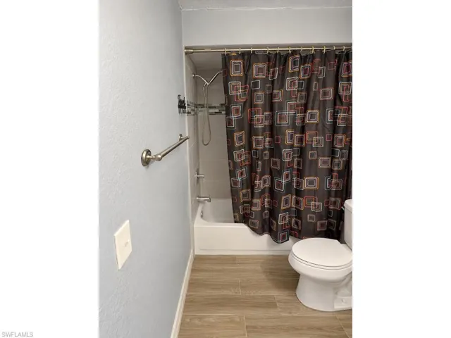 Bathroom featuring wood-finish flooring and a shower-over-tub combination with a subway tile surround