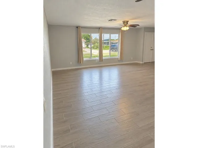 Wood-finish tile flooring throughout, neutral wall tones, multi-pane windows, and a ceiling fan with integrated lighting