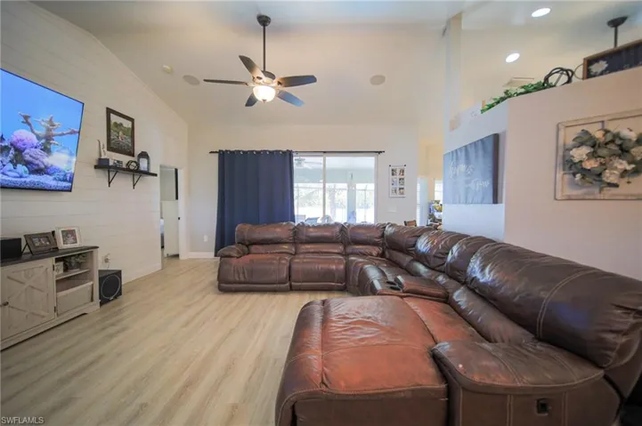 Living area with light wood-style floors, a ceiling fan, and high vaulted ceiling