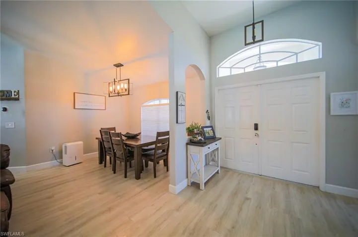 Foyer featuring a chandelier, arched walkways, light wood-style floors, plenty of natural light, and high vaulted ceiling