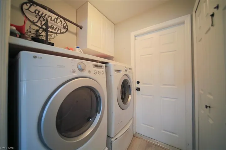 Laundry room featuring cabinet space, independent washer and dryer, and light wood finished floors