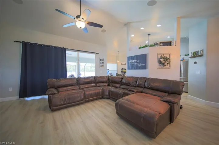 Living area featuring light wood-style floors, ceiling fan, and high vaulted ceiling
