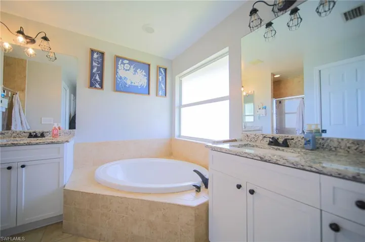 Bathroom with two vanities, a shower stall, a garden tub, and tile patterned flooring