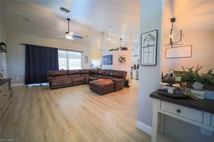 Living area with light wood finished floors, ceiling fan, a towering ceiling, and a chandelier