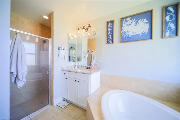 Full bath featuring vanity, a bath, tile patterned floors, and a shower stall