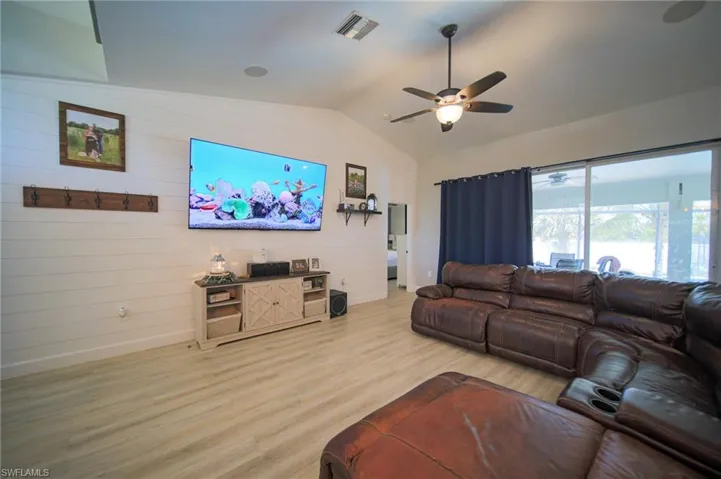 Living room featuring ceiling fan, wood finished floors, lofted ceiling, and wood walls