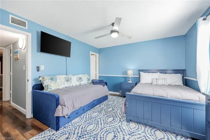 Bedroom featuring hardwood / wood-style flooring, ceiling fan, and a textured ceiling