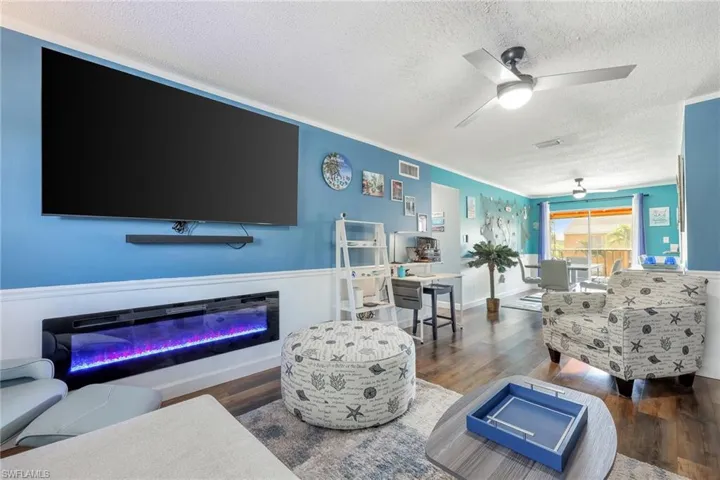 Living room with ceiling fan, dark hardwood / wood-style flooring, and a textured ceiling
