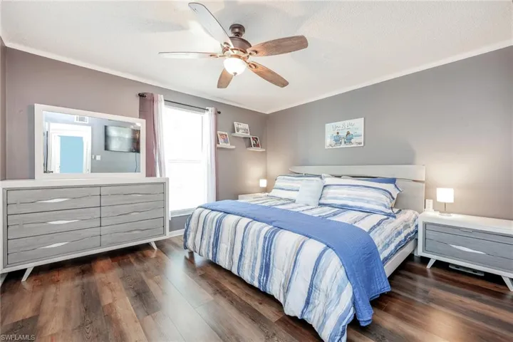 Bedroom with ceiling fan, crown molding, and dark wood-type flooring