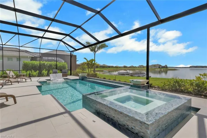 View of swimming pool featuring a water view, a pool with connected hot tub, a patio area, a lanai, and a sunroom