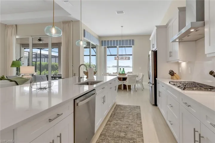 Kitchen featuring white cabinetry, wall chimney exhaust hood, and plenty of natural light