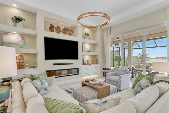Living room with built in features, a sunroom, and a glass covered fireplace