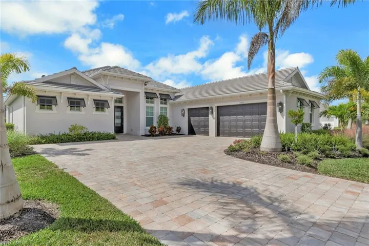 View of front of property with a tiled roof, decorative driveway, stucco siding, and a garage