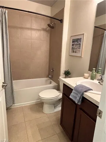 Bathroom with toilet, tile patterned flooring, shower / bath combo with shower curtain, and vanity