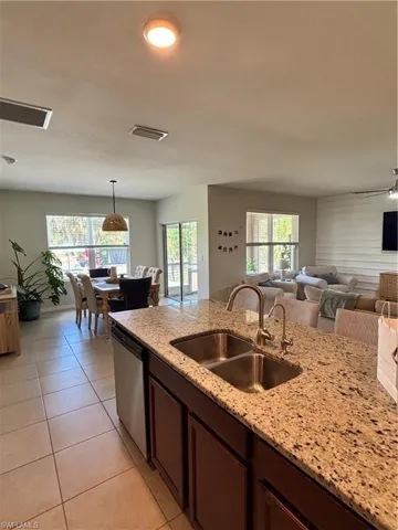 Kitchen with a sink, light tile patterned floors, visible vents, dishwasher, and open floor plan