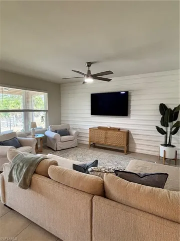 Living area featuring ceiling fan and wooden walls
