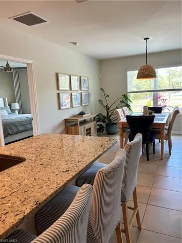 Kitchen featuring light tile patterned floors, light stone countertops, visible vents, and pendant lighting