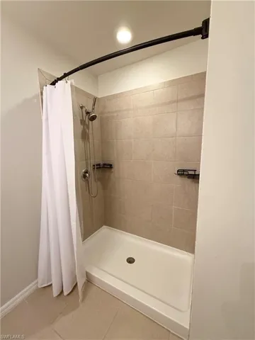 Bathroom with tile patterned floors and tiled shower