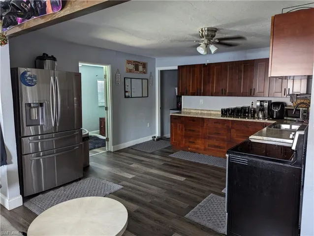 Kitchen featuring stainless steel fridge, black electric range, ceiling fan, dark wood-style floors, and light countertops