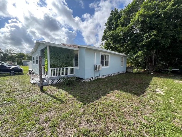 View of property exterior featuring covered porch, a lawn, and cooling unit