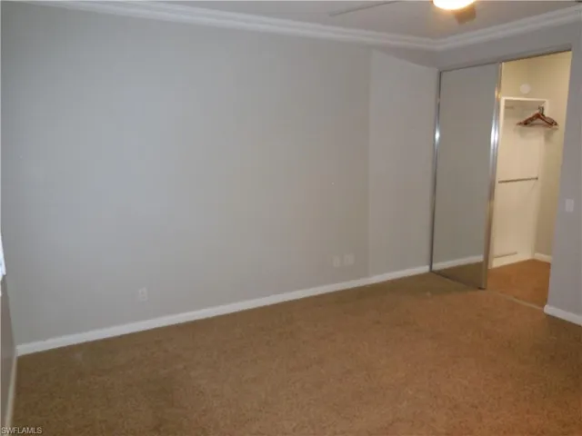 Unfurnished bedroom featuring ceiling fan, carpet floors, a closet, and crown molding