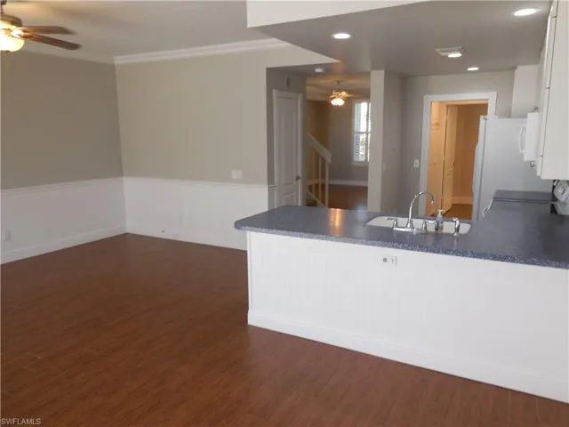 Kitchen with white cabinets, dark wood-type flooring, sink, kitchen peninsula, and crown molding