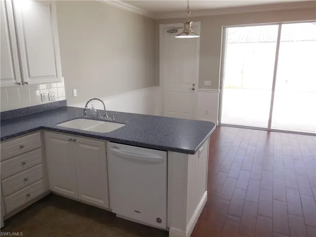 Kitchen featuring pendant lighting, white cabinetry, sink, and dishwasher