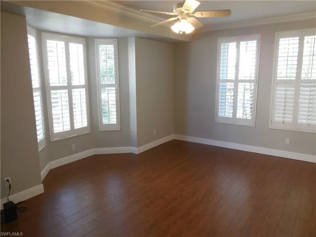 Unfurnished room with ornamental molding, ceiling fan, and dark wood-type flooring