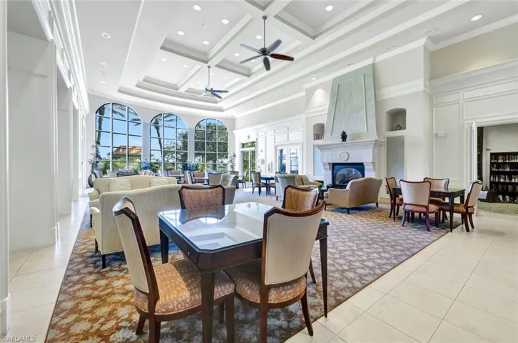 Dining area with ceiling fan, coffered ceiling, a large fireplace, a towering ceiling, and light tile patterned floors