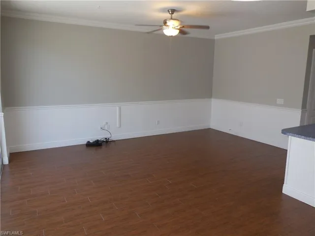 Spare room featuring dark hardwood / wood-style floors, ornamental molding, and ceiling fan