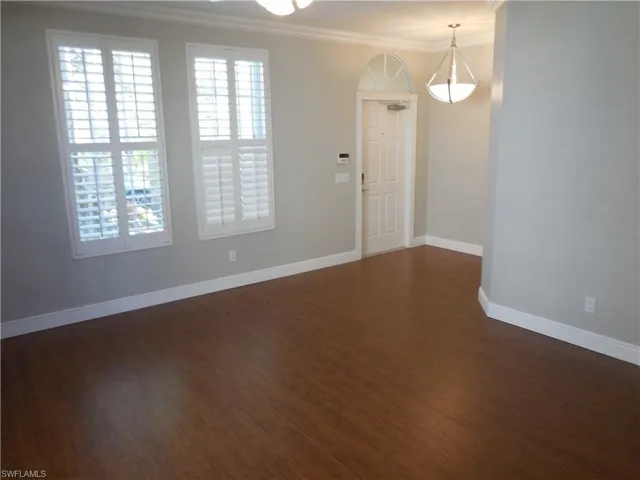 Empty room featuring dark hardwood / wood-style floors and ornamental molding