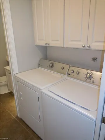 Laundry room with dark tile patterned floors and washer and clothes dryer