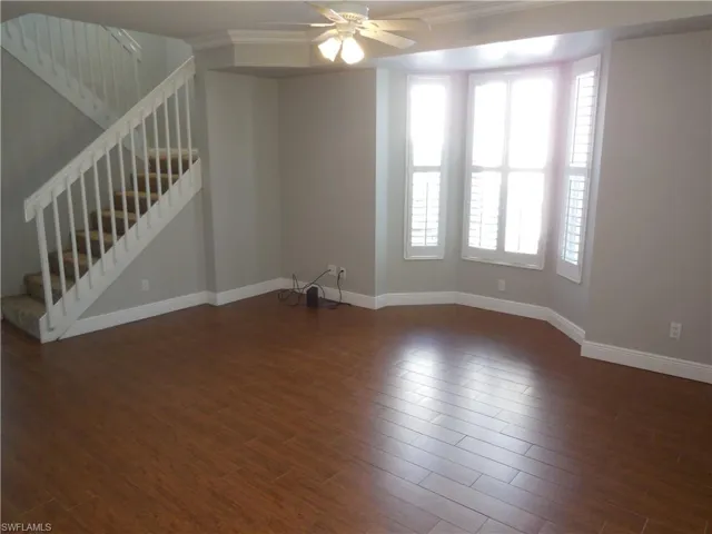 Spare room with crown molding, dark hardwood / wood-style flooring, and ceiling fan